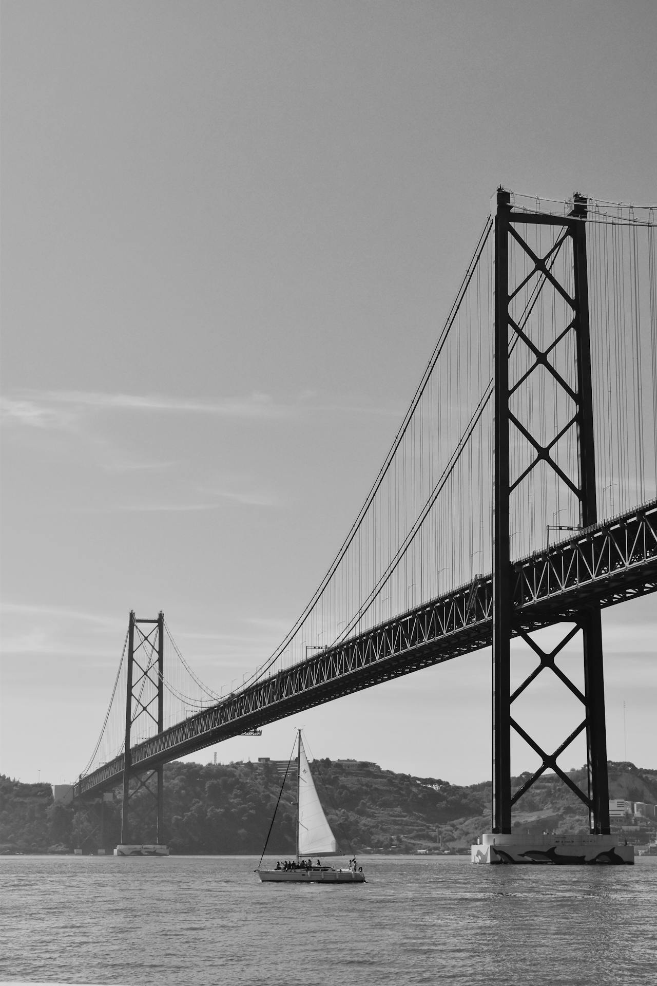 A sailboat sailing under a bridge in Lisbon.