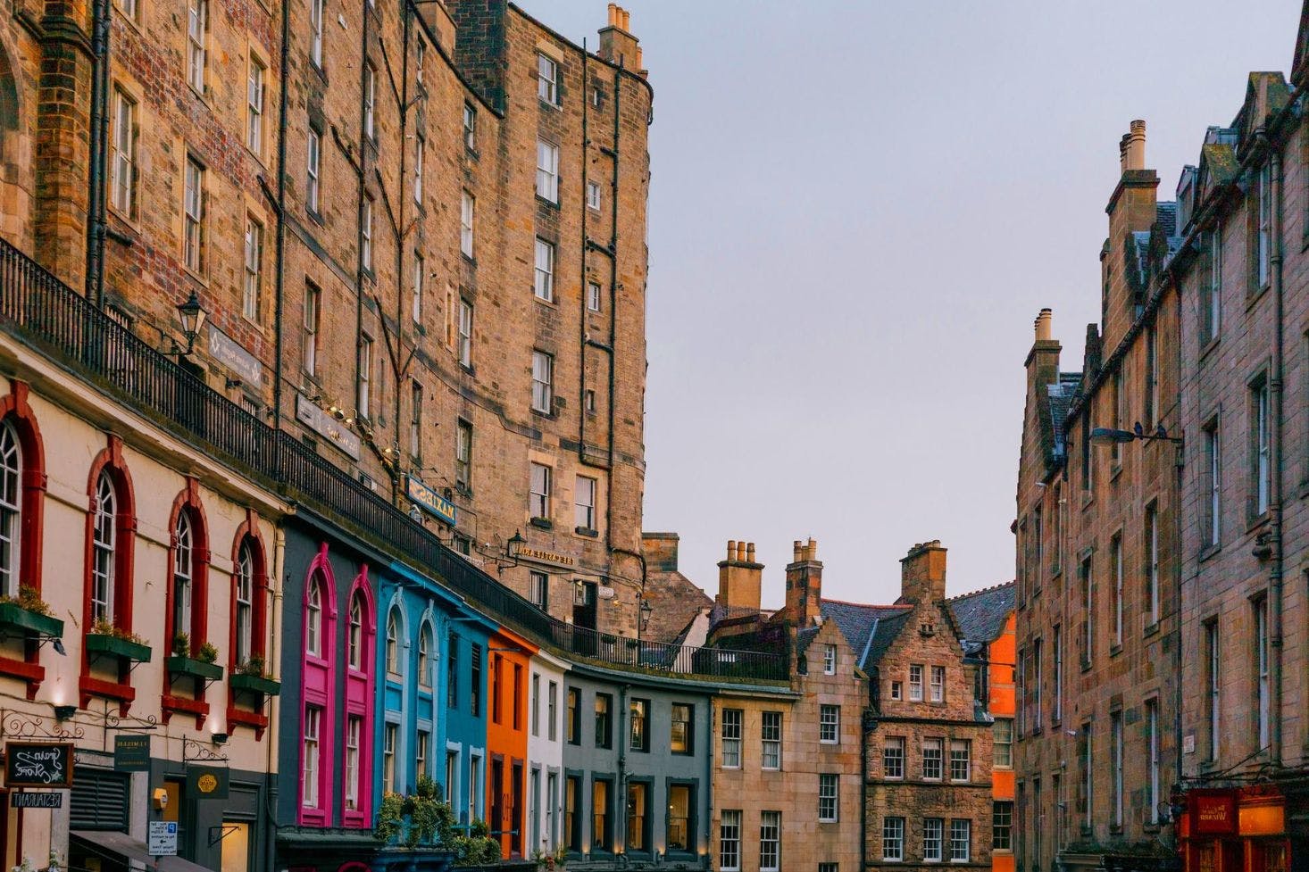 Colorful buildings along Victoria Street in Edinburgh against a backdrop of historic stone architecture