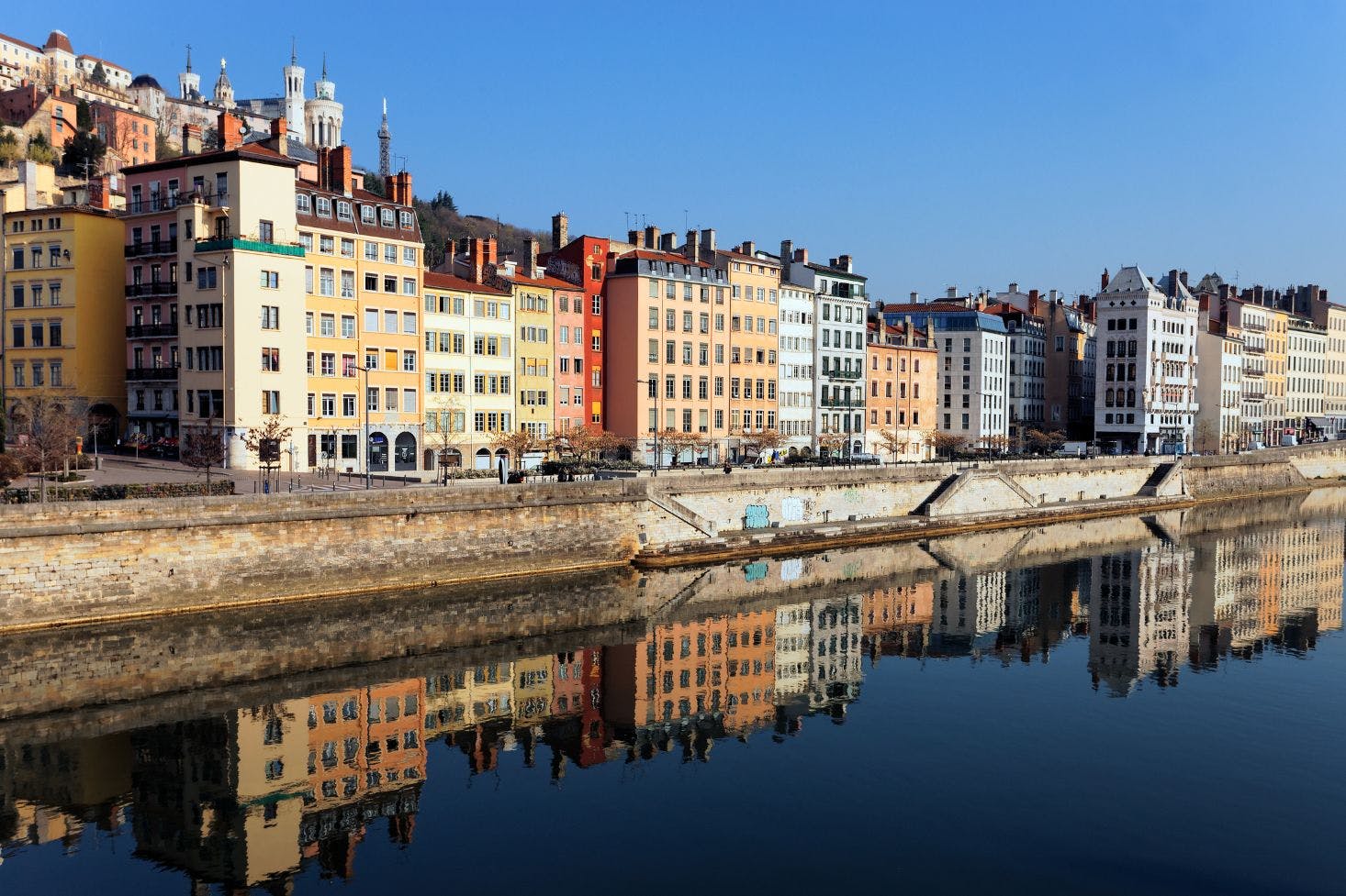 Colorful buildings line the Saône River in Lyon, France, with their reflections on the water