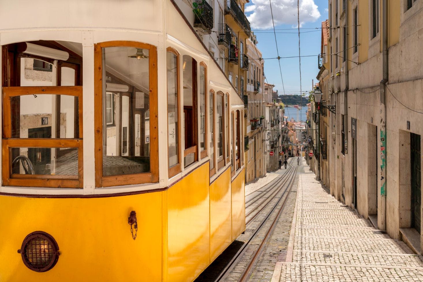 Yellow Bica Elevator in Lisbon, steep street sloping towards the river with buildings lined along the path