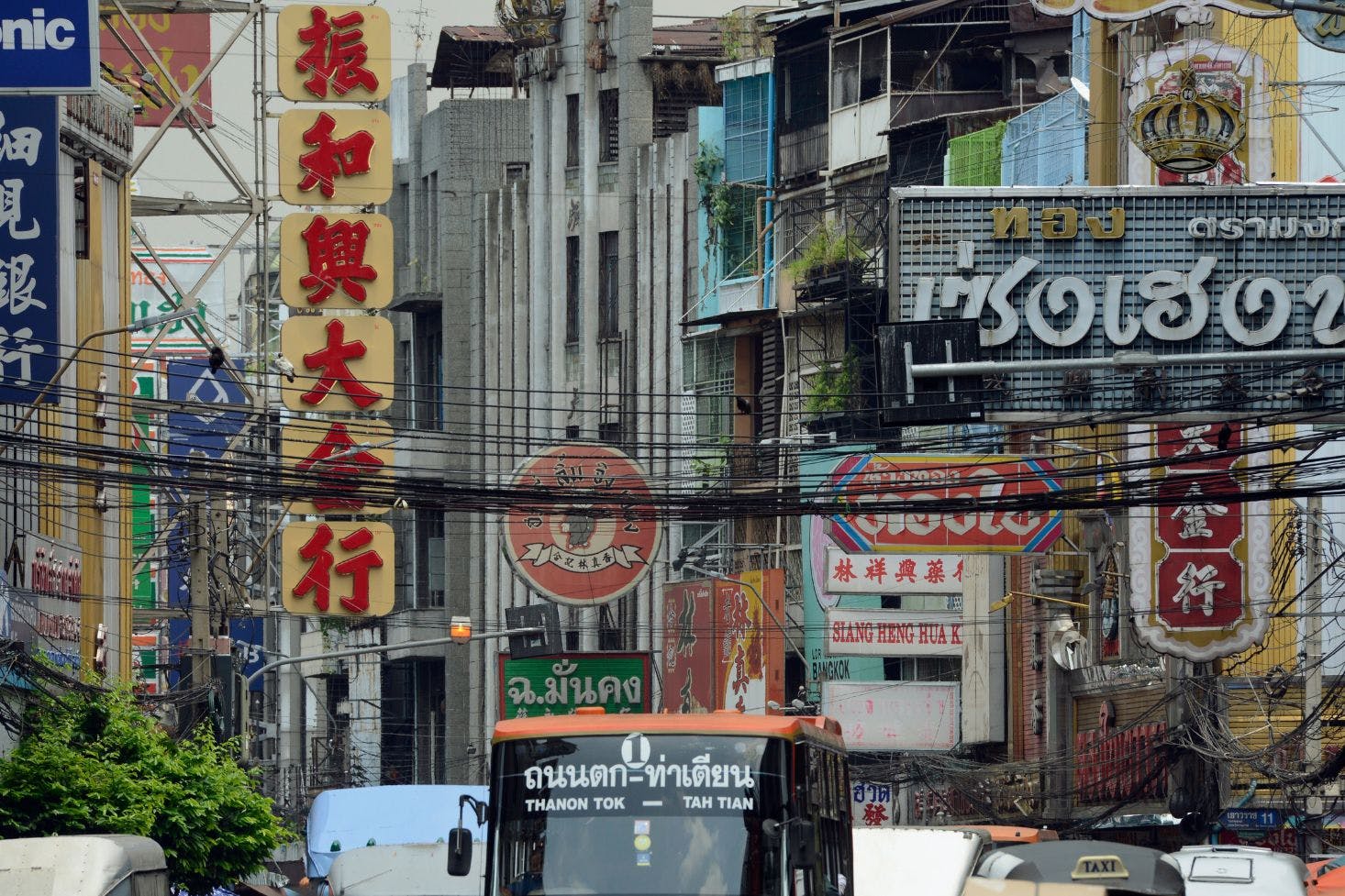 Busy Bangkok street filled with colorful ads on buildings, buses, and cars