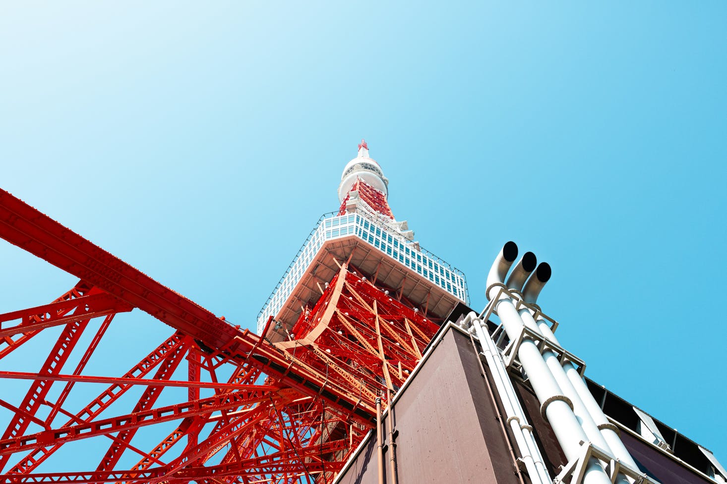 Close-up view from the ground looking up at the red and white Tokyo Tower