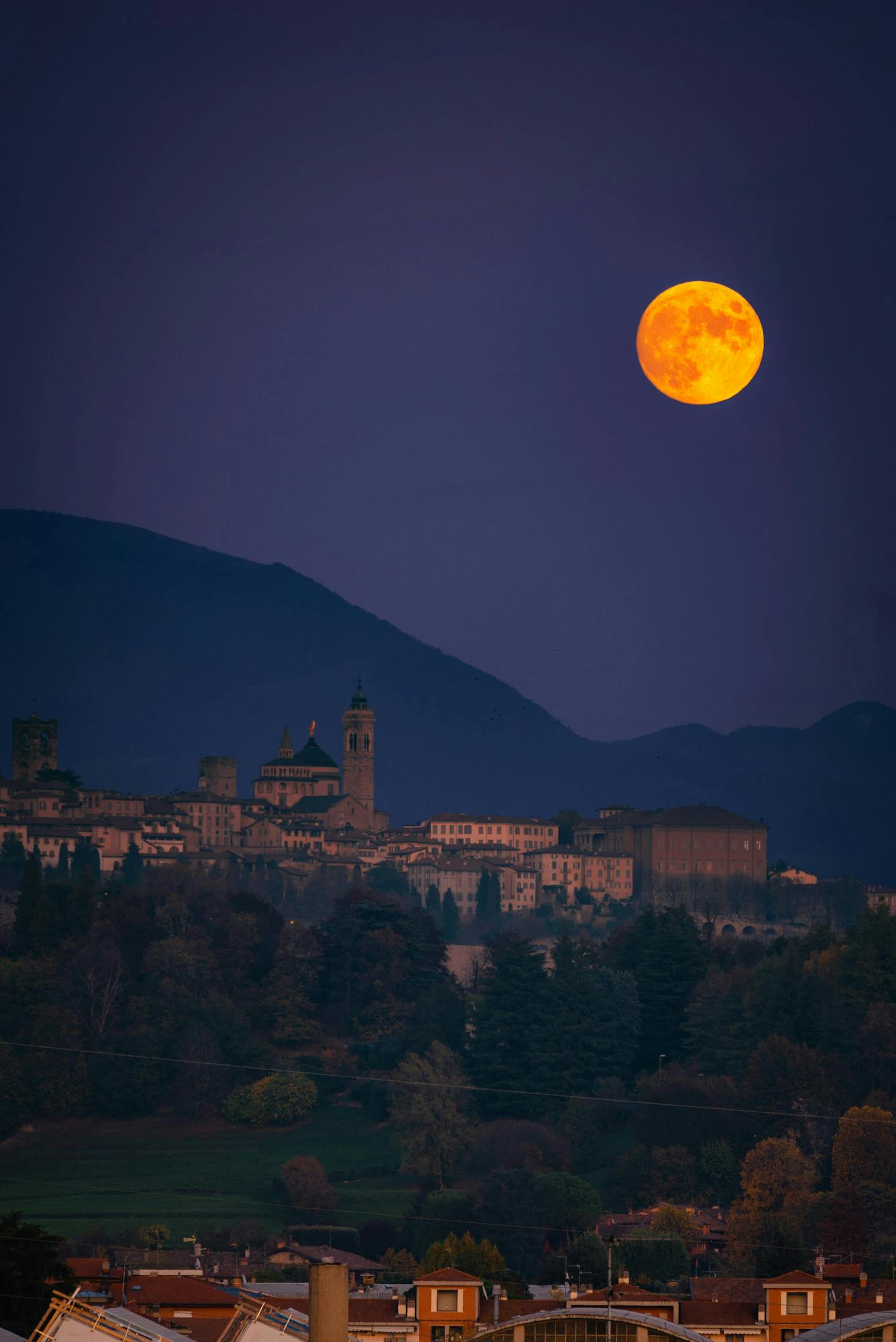 The large moon over the hills of Bergamo at night