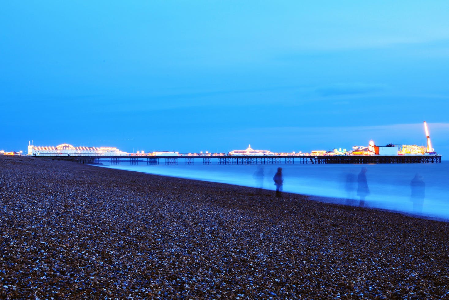 People walking on the beach at dusk in Bright with the pier in the distance