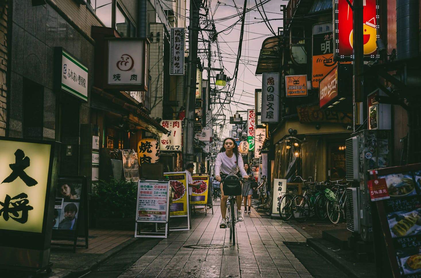 A person riding a bike past the many storefronts in Tokyo's Nakano City