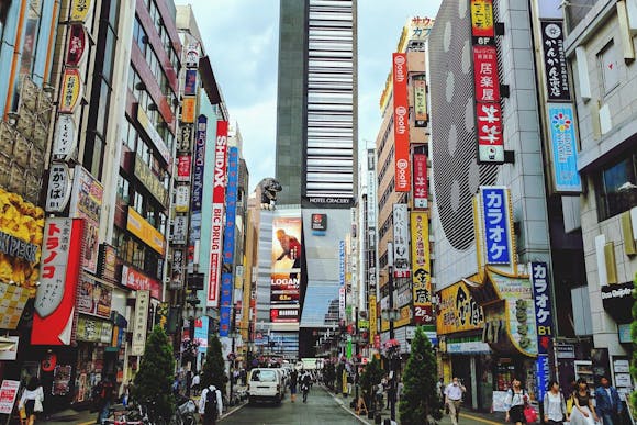 A busy Tokyo street with colorful ads and inscriptions and people weaving through the cityscape