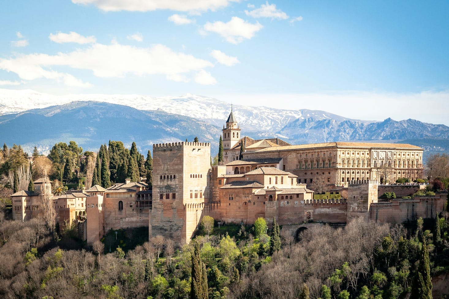 Edifici dell'Alhambra a Granada, con Sierra Nevada sullo sfondo e cielo azzurro 