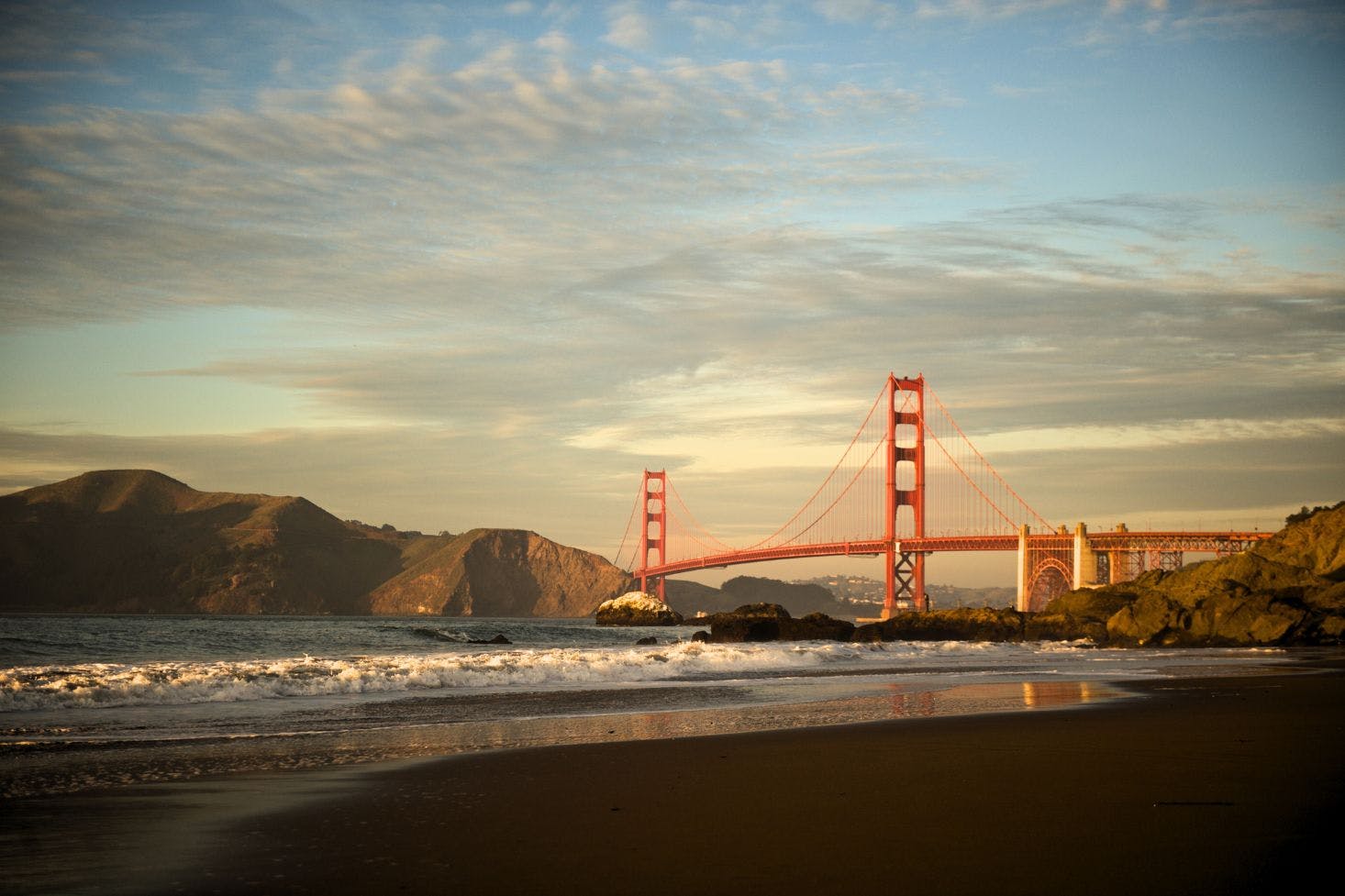 View of the San Francisco Golden Gate Bridge, surrounding mountains, beach, and the sea