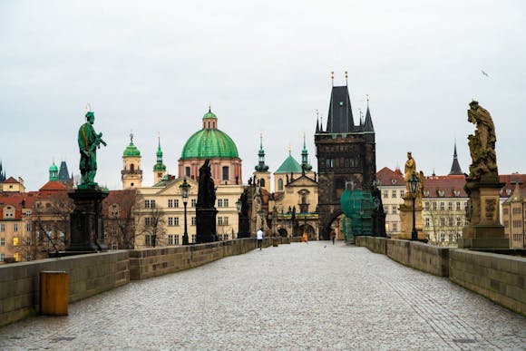 View of the cobblestone Charles Bridge, its ornate sculptures, the Old Town Hall, and St. Nicholas Church