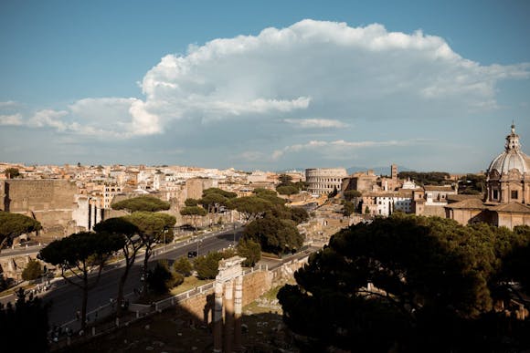 Rome cityscape featuring the Colosseum, Vittorio Emanuele II Monument, St. Luca e Martina dome, and surrounding buildings.