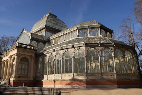 A wide view of the Palacio de Cristal in Madrid, showcasing its glass structure and surrounding greenery