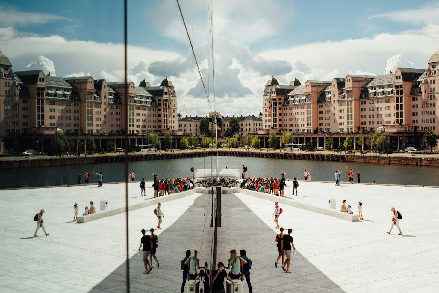 The modern mirrored facade of the Oslo Opera House reflecting the surrounding buildings and people