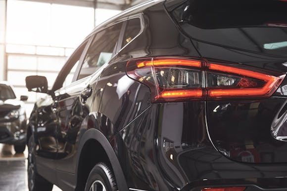 Close-up of a sleek black SUV with illuminated taillights, showcased in an indoor setting