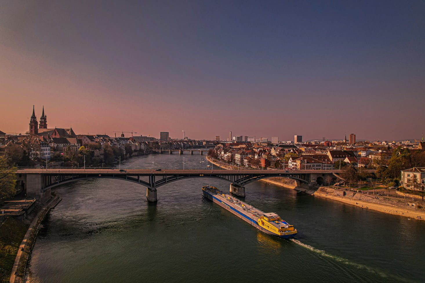 Grande ponte sul fiume Reno, con edifici della città di Basilea ai lati, al tramonto