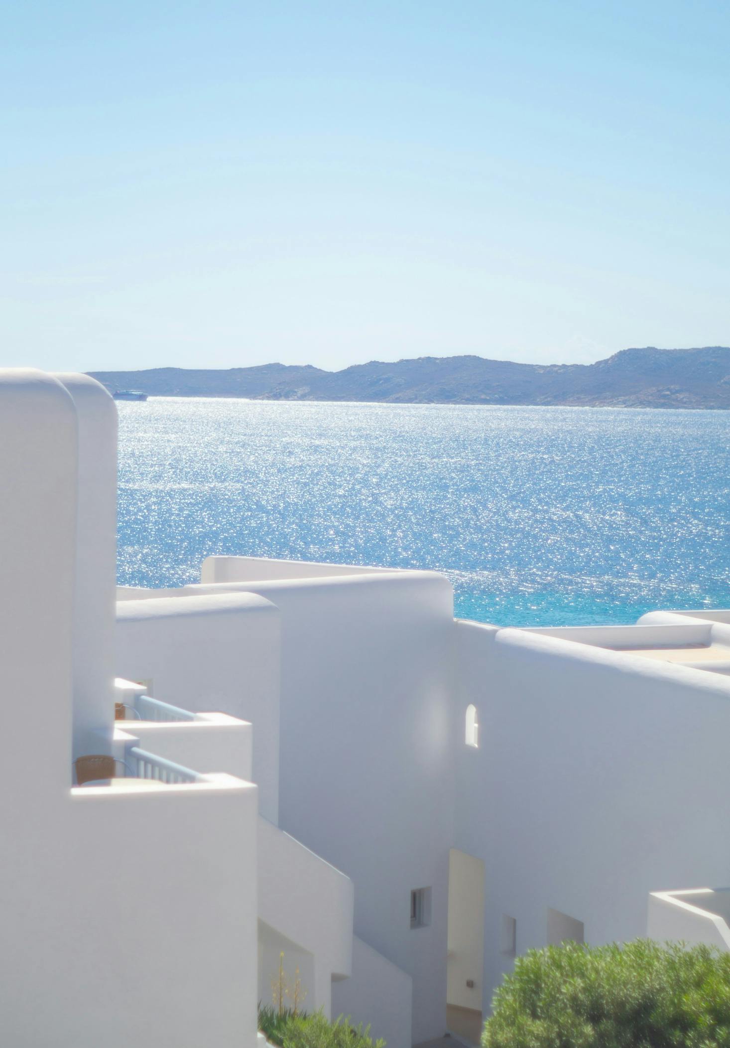 Murs blancs face à l'eau avec des montagnes en fond à Mykonos, Grèce