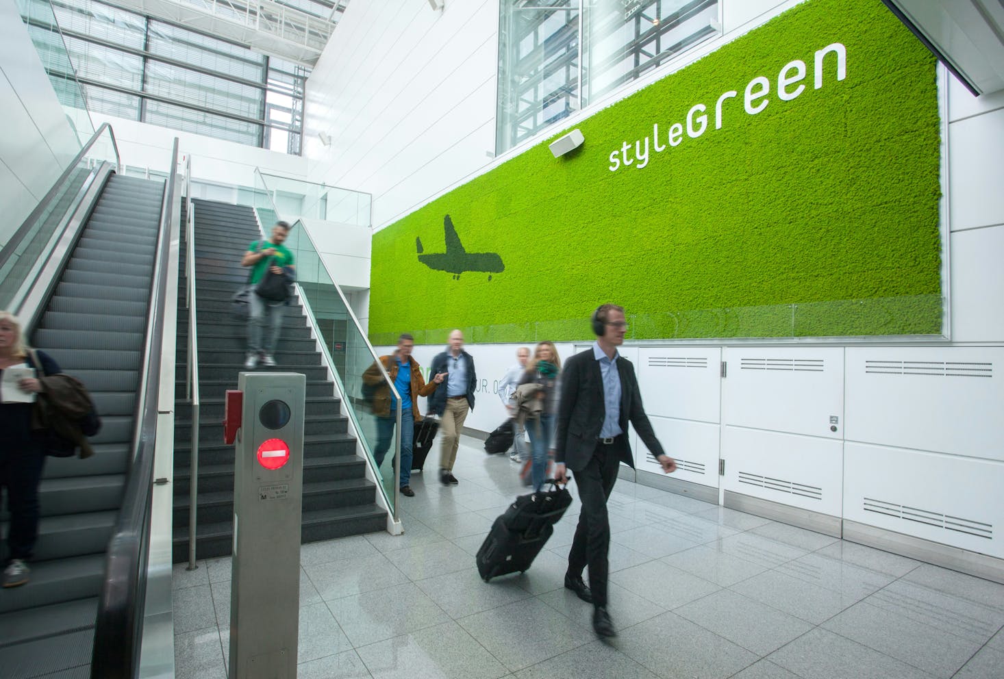 Interni dell'aeroporto di Monaco di Baviera, scale mobili e persone con trolley che si muovono