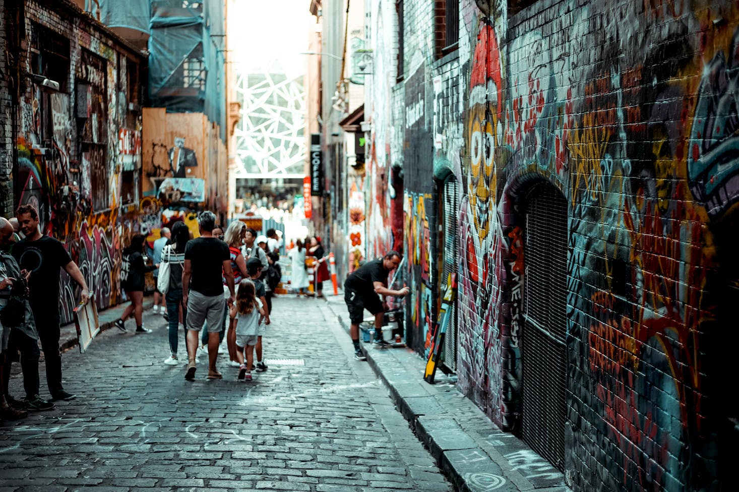 People walking through an alleyway in Melbourne full of colorful graffiti