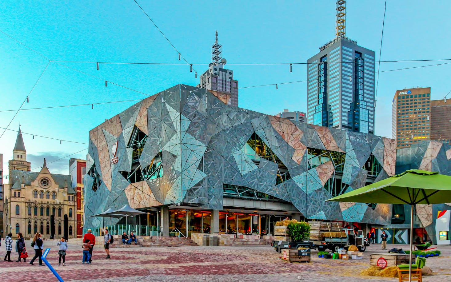 People setting up for an even in Melbourne's Fed Square flanked by a mix of modern and historic buildings