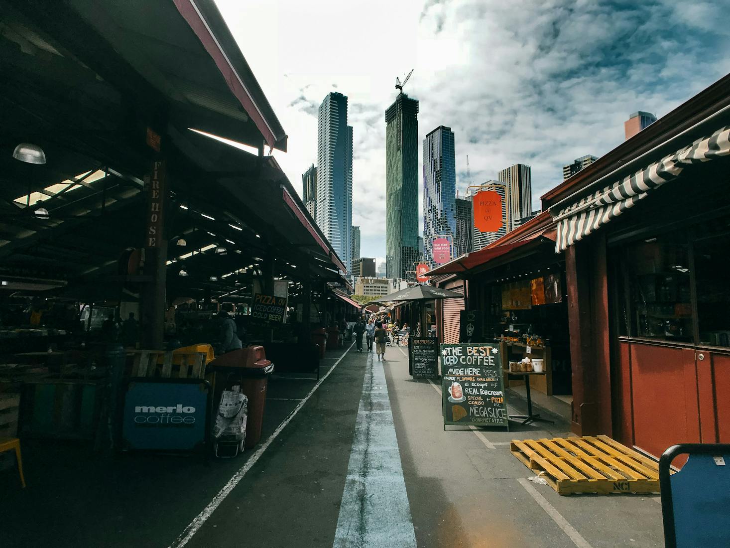 The stalls of the Queen Victoria Market in Melbourne with skyscrapers in the distance