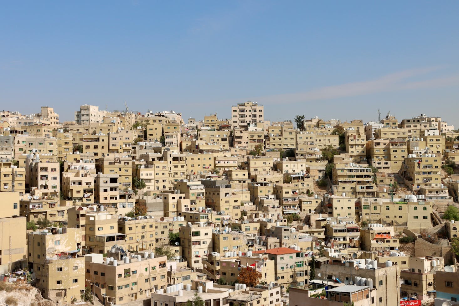 View from the Citadel in Amman of uniform light brown apartment buildings and blue sky