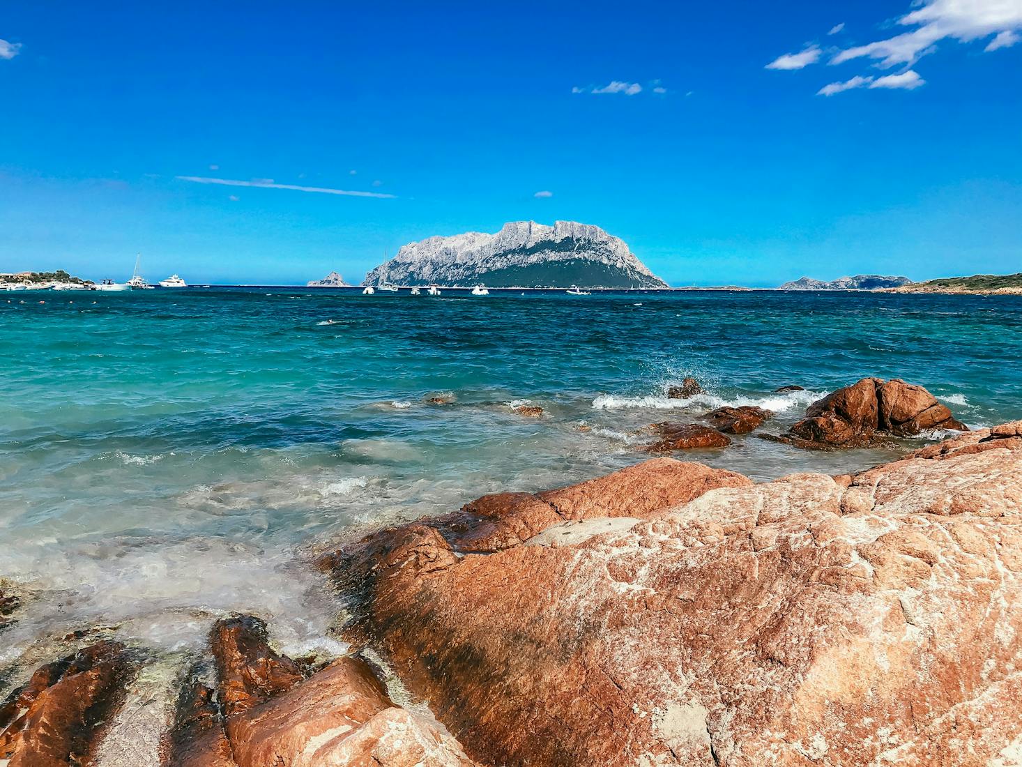 Mare cristallino di Sassari, con scogli in primo piano e cielo azzurro sullo sfondo