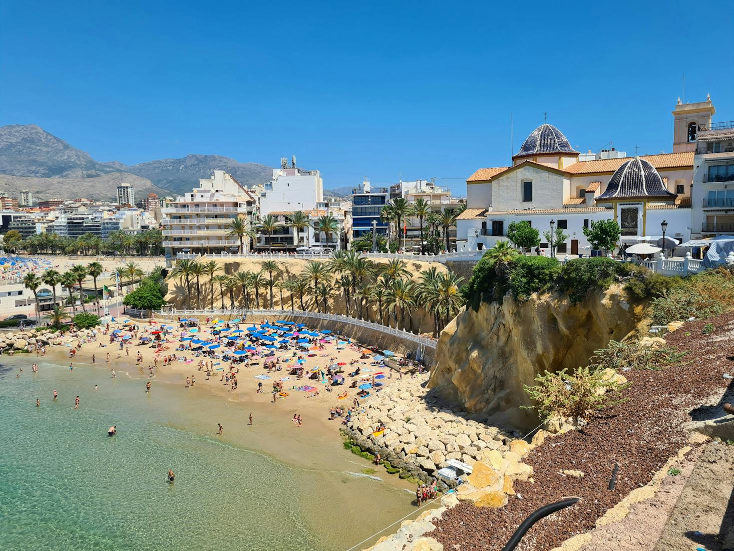 Spiaggia con ombrelloni a Benidorm, con mare sulla sinistra e edifici sullo sfondo