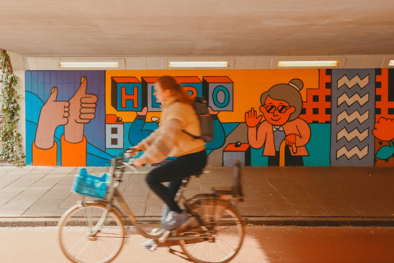 Ragazza in bicicletta a Eindhoven, con murales alle sue spalle