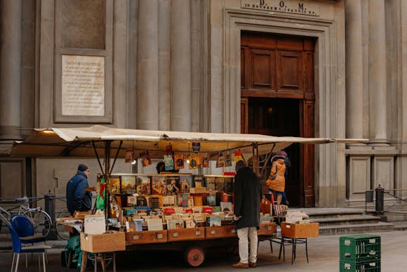 A man browsing a bookstand in front of the San Giovannino degli Scolopi church in Florence