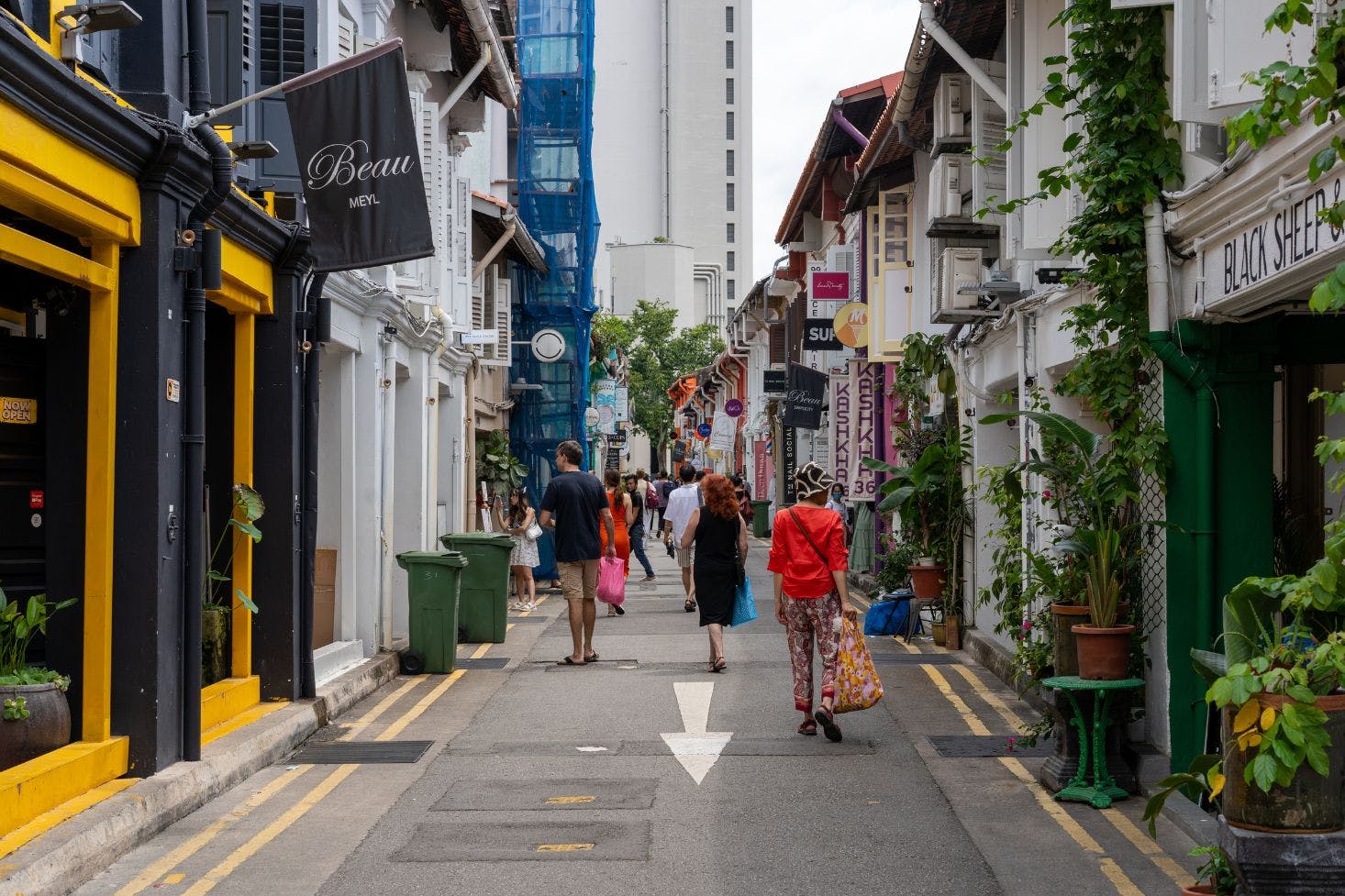 Haji Lane in Singapore, busy with shoppers carrying bags and colorful shops along the street