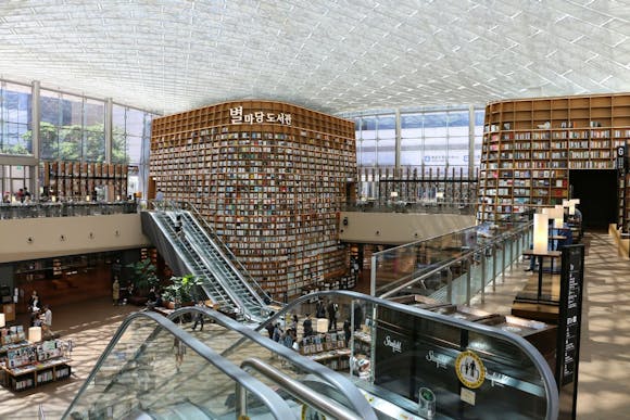 Starfield Library at Seoul Coex Mall, with towering bookshelves, two escalators, and bustling shoppers exploring the space