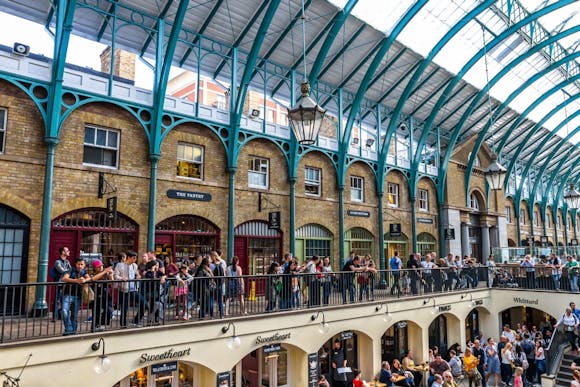 Covent Garden Market's interior with iconic blue details and two floors of shops busy with shoppers