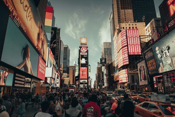 Busy Times Square with yellow cabs, bright flashing ads, and shops lining the street