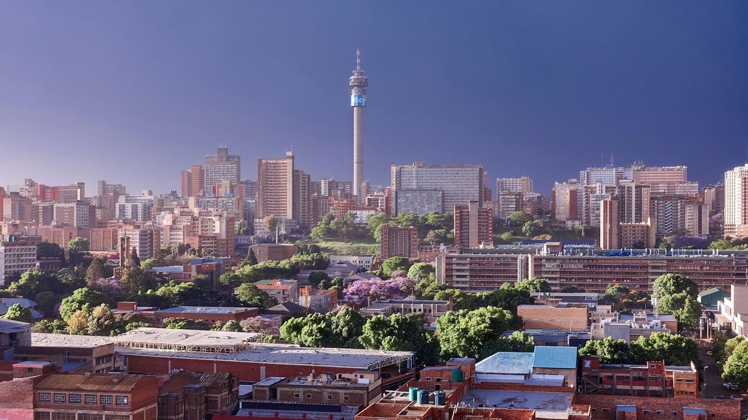 Downtown Johannesburg with a prominent tower in the skyline with dark clouds in the distance