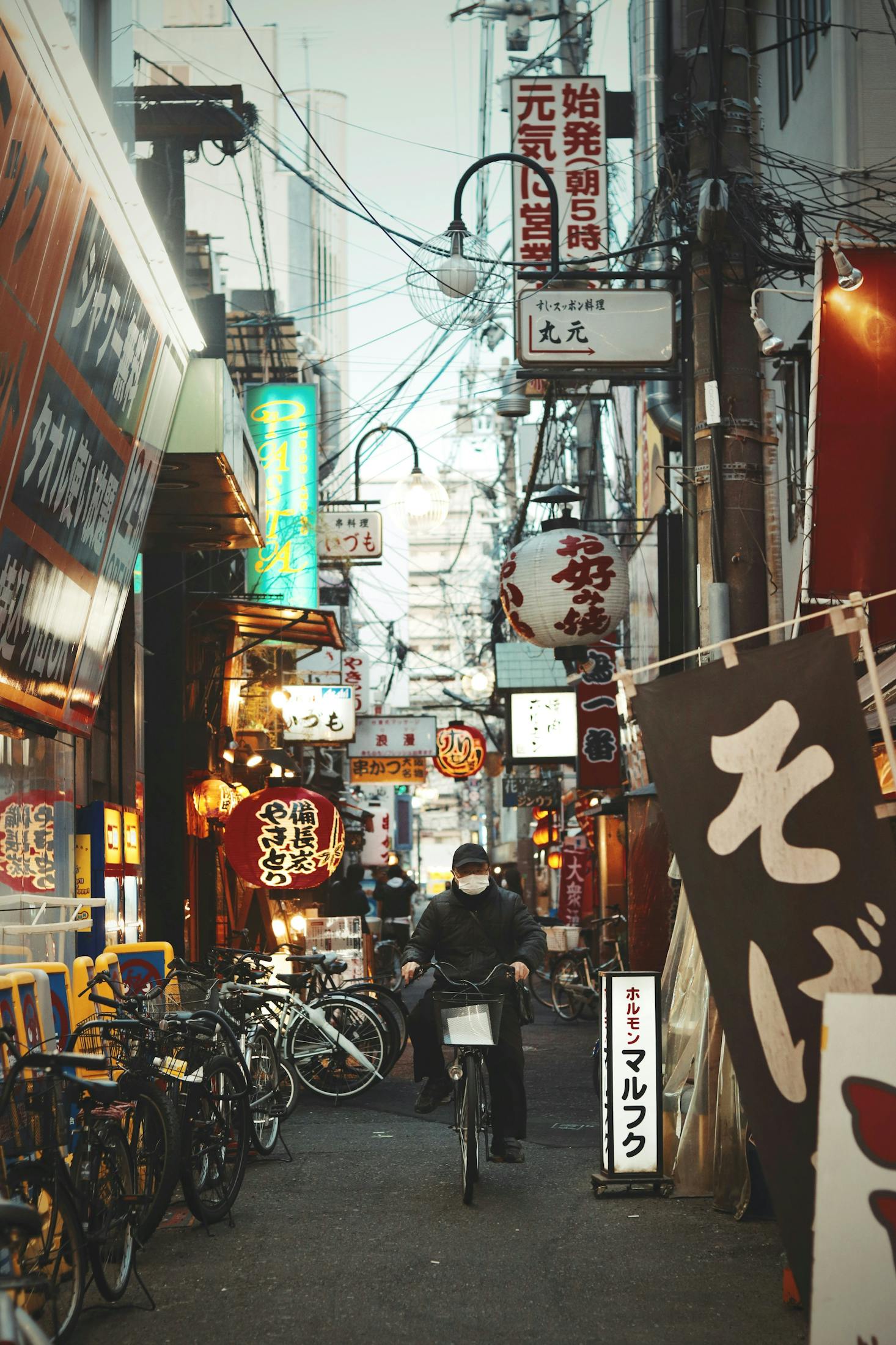 A street cluttered with signs and bicycles in Osaka