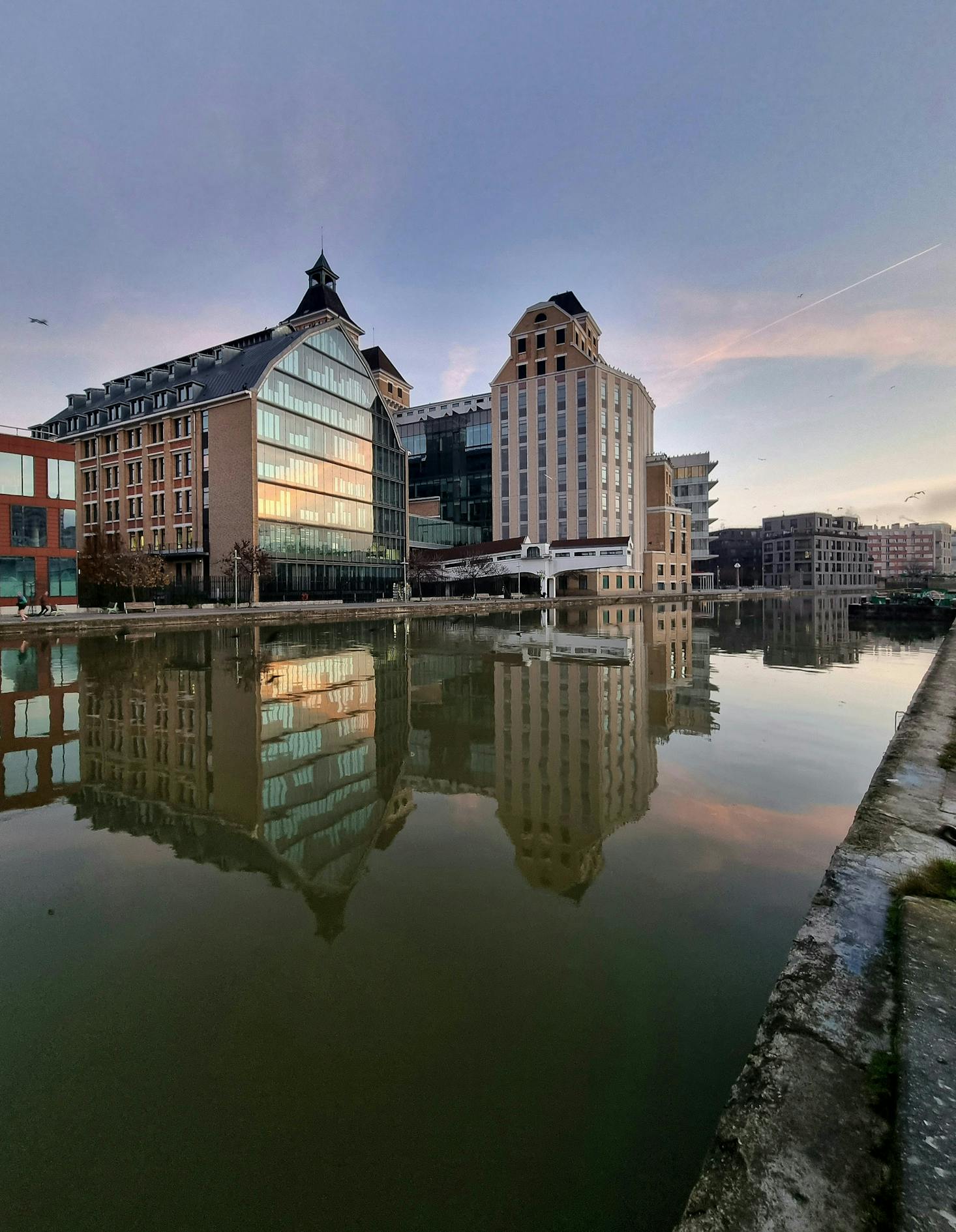 Deux grandes maisons face à l'eau sous un ciel crepusculaire à Pantin, France