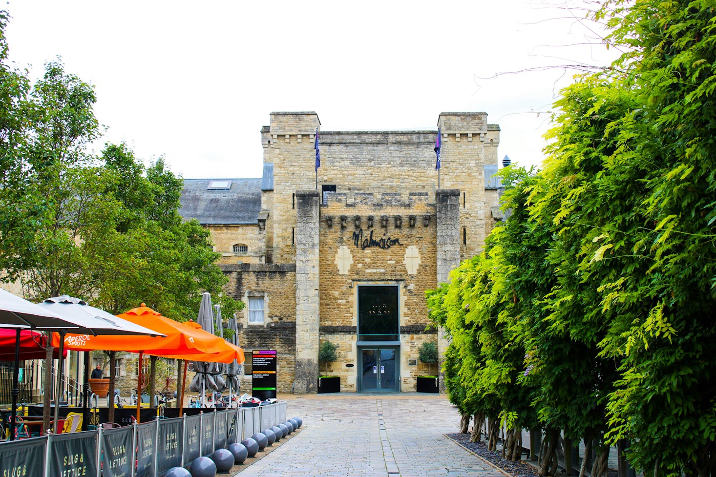 Outdoor restaurants in Oxford in front of a historic building on a cloudy day