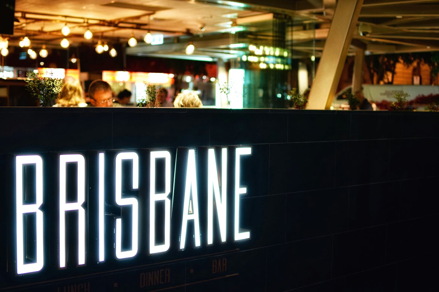 White neon "Brisbane" sign at a restaurant