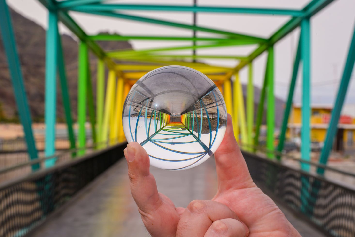 The reflection of a colorful bridge in a hand-held marble in Tenerife