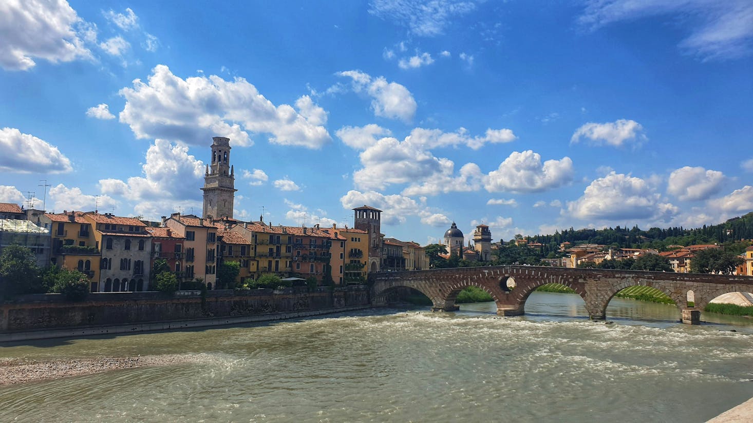 Ponte Pietra spanning the river in Verona with historical buildings on the banks