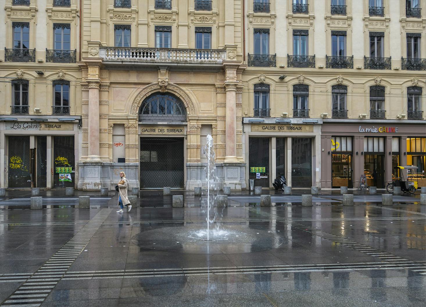 A square in Lyon on a rainy day with a single person walking through