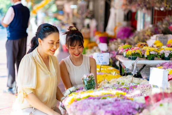 Happy Asian mother and daughter choosing and buying fresh flowers together at a flower market