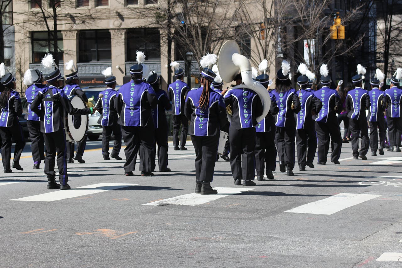 Marching band members in purple and black uniforms performing during a parade