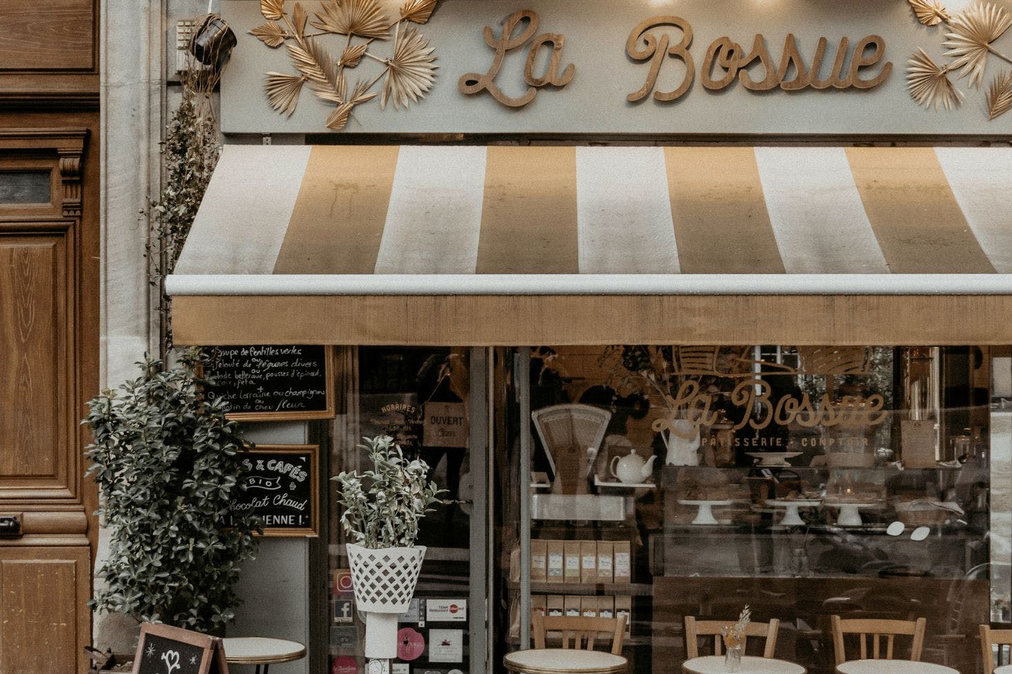 Strret view of 'La Bossue' patisserie in Paris, with outdoor tables and chairs