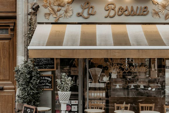 Strret view of 'La Bossue' patisserie in Paris, with outdoor tables and chairs