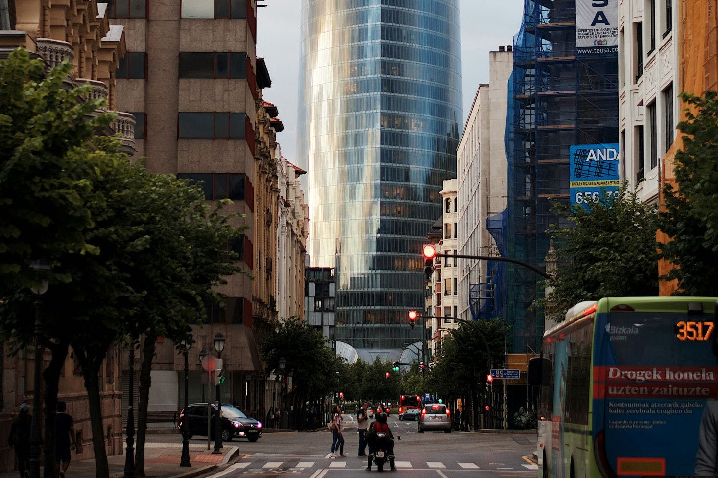 Busy boulevard with cars and a bus with the view of Iberdrola Tower, a skyscraper