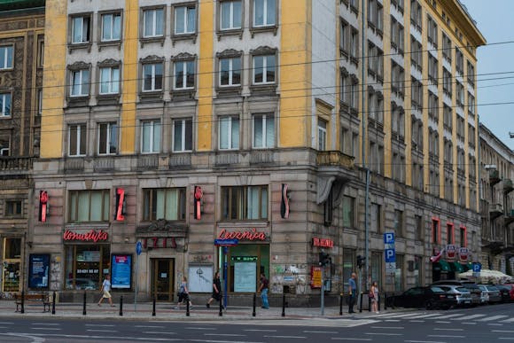 A busy shopping street in Warsaw Old Town with locals passing by the old building with shops