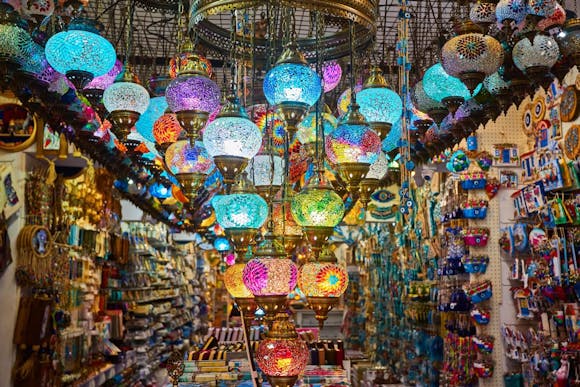 A market stall filled with colorful mosaic Turkish lamps hanging from the ceiling and walls packed with trinkets and crafts