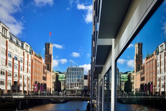 View of the Hamburg skyline with the Elbe River, a bridge, the Port Clock Tower, and nearby shops