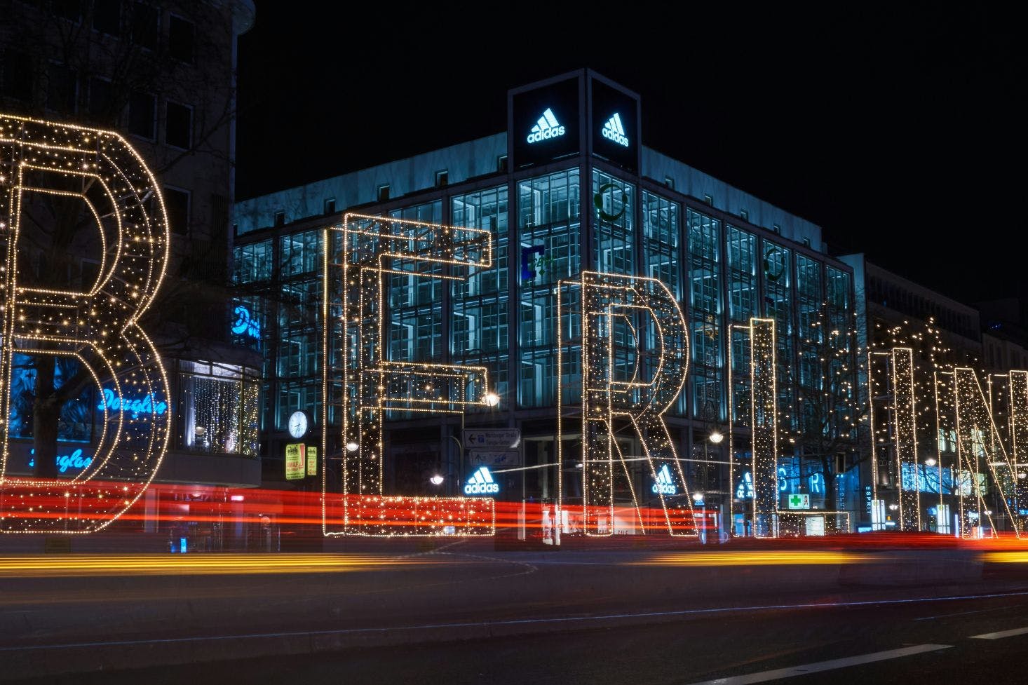 The sparkling "Berlin" sign in front of a department store with shops like Adidas and Douglas