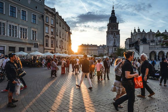 Busy Main Market Square in Krakow with a lot of pedestrians with shopping bags passing by